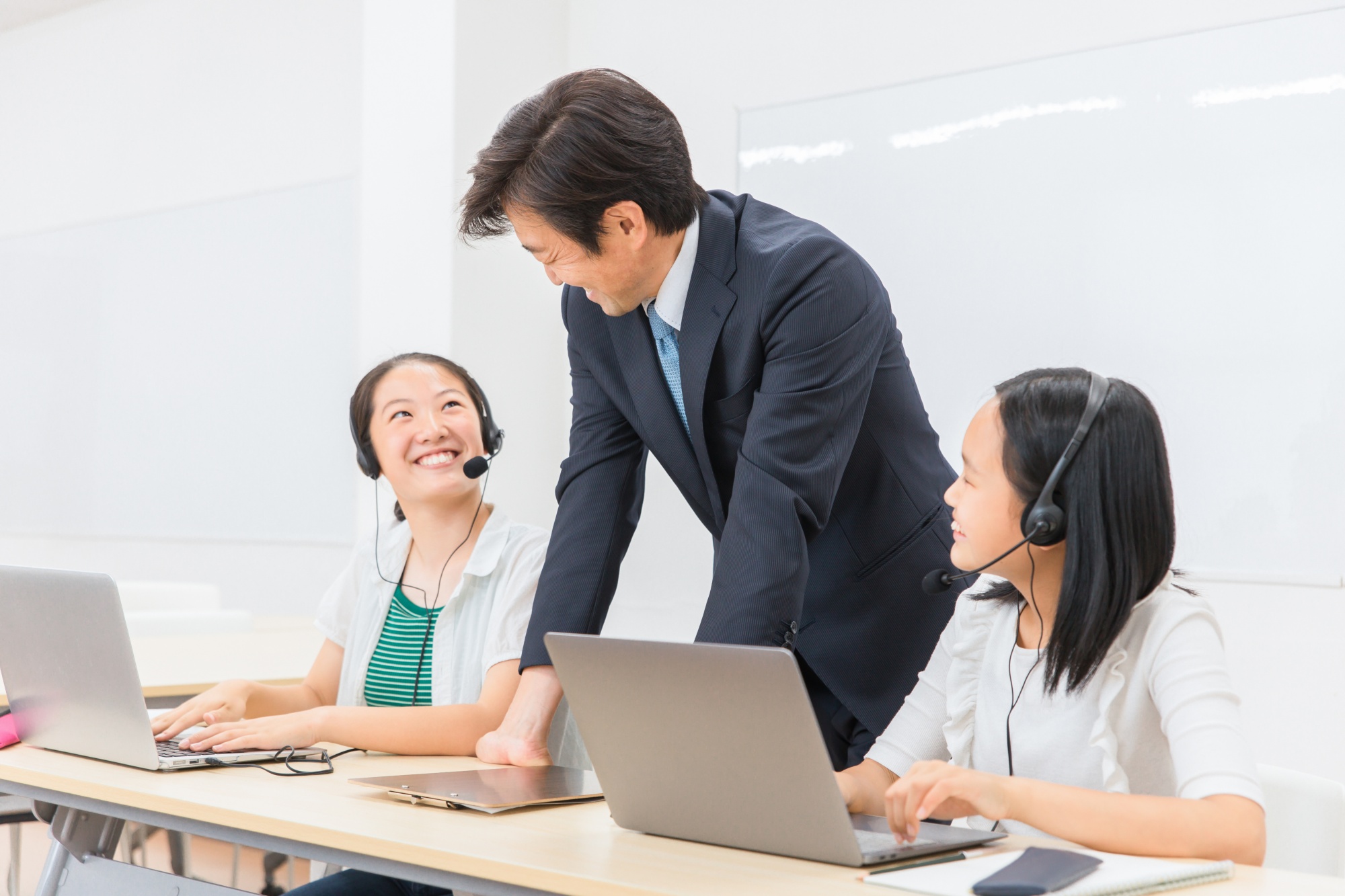 学校の授業・塾でで英会話のリスニング・ヒアリングレッスンをする先生・教師と子供（女の子・日本人）